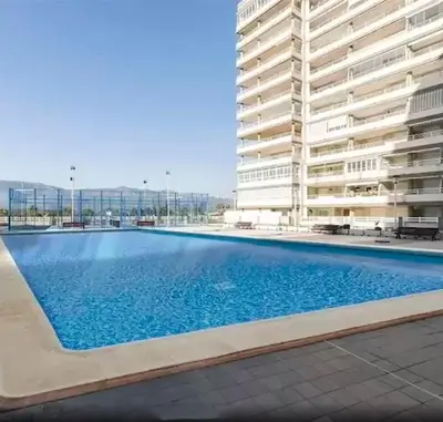 a large swimming pool with blue water in a building at Apartamento en urbanización lujo in Tavernes de Valldigna