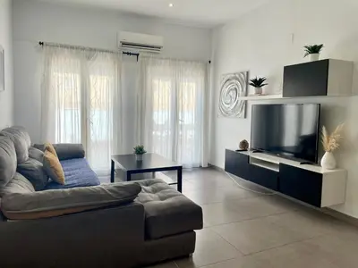 a living room with a couch and a flat screen tv at UIM Mediterraneo ATICO Hipanidad 1 WIFI in Puerto de Sagunto