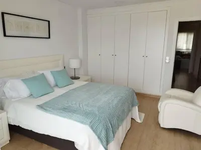 a bedroom with a bed with a blue blanket and a chair at Villa de lujo frente al mar in Barrio-Mar