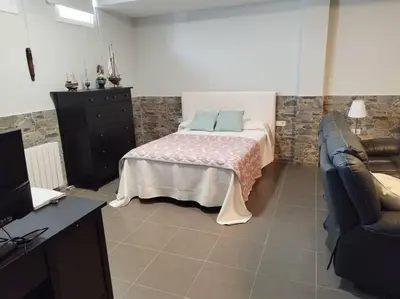 a bedroom with a bed and a tv and a couch at Villa de lujo frente al mar in Barrio-Mar