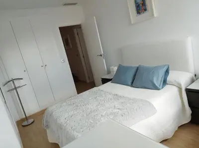 a white bedroom with a bed with blue pillows at Villa de lujo frente al mar in Barrio-Mar