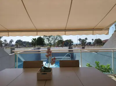 a table and chairs with an umbrella on a balcony at Villa de lujo frente al mar in Barrio-Mar