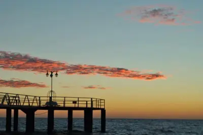 a pier on the beach with a sunset at Apartamento Margalló con Garaje in Xilxes