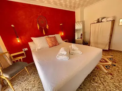 a bedroom with a large white bed with a red wall at Mountain Retreat with stunning terrace views in Pedralba