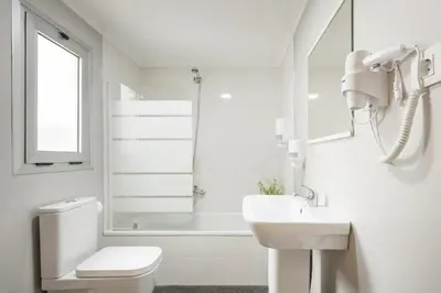 a white bathroom with a toilet and a sink at Macflats Ciudad de las Ciencias in Valencia
