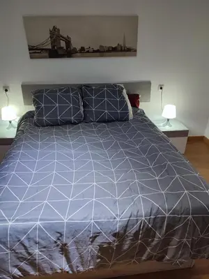 a bed with a blue comforter and two lamps at Bedroom to rent in the beach in Valencia