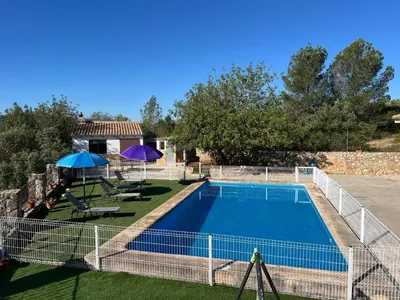 a swimming pool in a yard with two umbrellas at Casa El Calderon in Chella