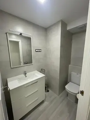 a bathroom with a sink and a toilet and a mirror at Apartamento de lujo en Cullera con Aire Acondicionado in Cullera