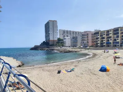 a beach with people and buildings and the ocean at Encantador piso cerca de la playa en Cullera in Faro de Cullera