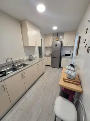 a kitchen with white cabinets and a table and a refrigerator at Precioso apartamento reformado con terraza, 4 habs in Valencia