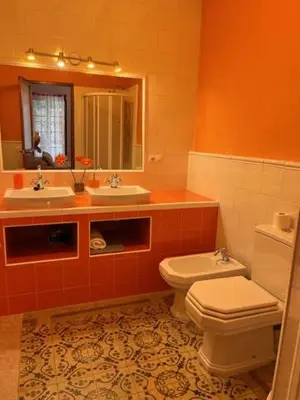 a bathroom with two sinks and a toilet and a mirror at Casa rural La Boticaria in Villar del Arzobispo