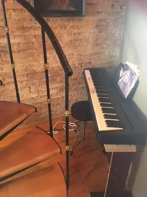 a piano and a chair next to a brick wall at Attic Duplex Ruzafa in Valencia
