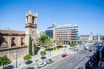 a city with a clock tower and a street with cars at Puerto Beach suites in Valencia