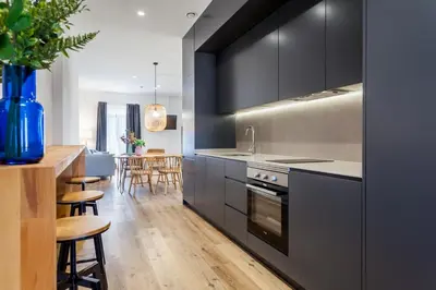 a kitchen with black cabinets and a dining room at Puerto Beach suites in Valencia