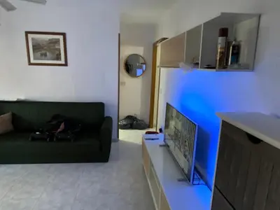 a living room with a green couch and a tv at Beautiful apartment 1 minute walk to the beach in Puerto de Sagunto