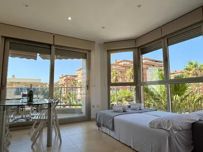 a bedroom with a bed and a table and windows at Reinapart Patacona Beachfront Seaview in Valencia