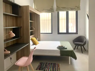 a small bedroom with a bed and two chairs at Habitación en Playa Malvarrosa con baño privado -No AC- in Valencia