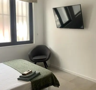 a bedroom with a chair and a tv on the wall at Habitación en Playa Malvarrosa con baño privado -No AC- in Valencia