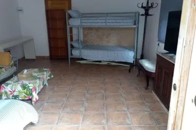 a room with a tiled floor with a bed and a television at Casa Tena in Partida de La Cañada