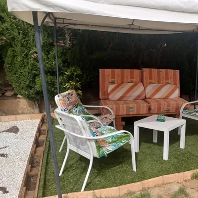 a patio with a couch and chairs under an umbrella at Casa Tena in Partida de La Cañada