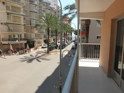 a balcony of a building with a street and palm trees at Neptuno Playa San Antonio in Cullera