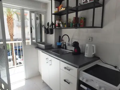 a kitchen with white cabinets and a sink and a window at Neptuno Playa San Antonio in Cullera