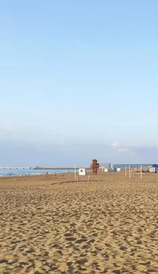 a sandy beach with a volleyball court and the ocean at VoraMar 3 Playa Puerto de Sagunto in Sagunto