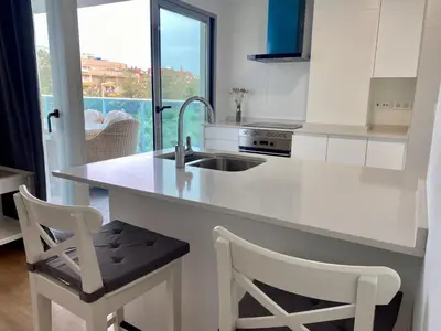 a kitchen with a sink and a counter with two chairs at VoraMar 3 Playa Puerto de Sagunto in Sagunto