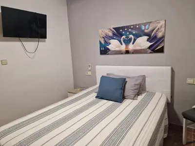 a bedroom with a white bed with a blue pillow at Habitaciones Zoe in Puerto de Sagunto