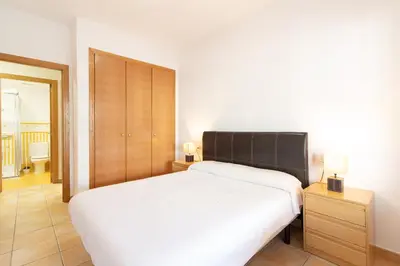 a bedroom with a white bed and a wooden cabinet at Global Vacacional, Apartamento con gran terraza en Canet in Canet de Berenguer