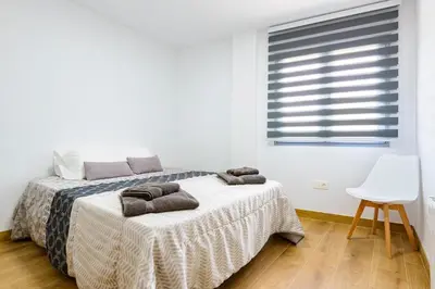 a white bedroom with a bed and a white chair at Un endroit accueillant avec vue à Jerica in Jérica