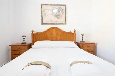 a bedroom with a bed with white sheets and two dressers at Global Vacacional, Apartamento en primera línea de playa, Canet de Berenguer in Canet de Berenguer