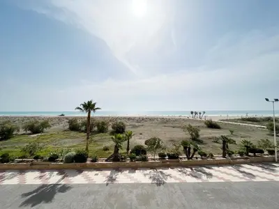 a view of a beach with palm trees and the ocean at Global Vacacional, Apartamento en primera línea de playa, Canet de Berenguer in Canet de Berenguer