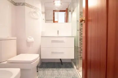 a white bathroom with a toilet and a sink at Global Vacacional, Apartamento en primera línea de playa, Canet de Berenguer in Canet de Berenguer