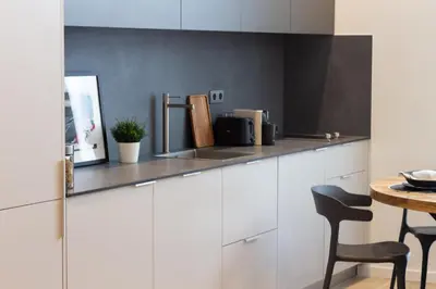 a kitchen with white cabinets and a table with a chair at VLC HOST - Cubells in Valencia
