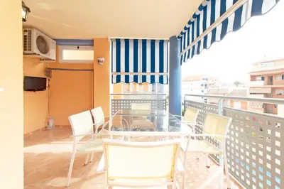 a balcony with a glass table and white chairs at Global Vacacional, Apartamento con piscina y terraza en Canet playa in Canet de Berenguer