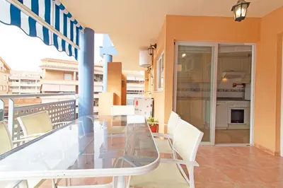 a balcony with a glass table and white chairs at Global Vacacional, Apartamento con piscina y terraza en Canet playa in Canet de Berenguer