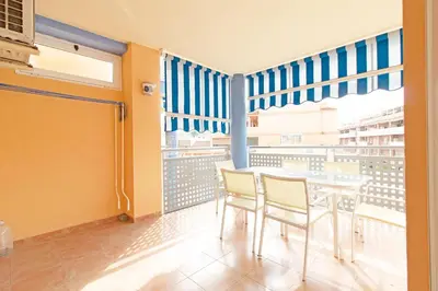 a room with a table and chairs and a balcony at Global Vacacional, Apartamento con piscina y terraza en Canet playa in Canet de Berenguer