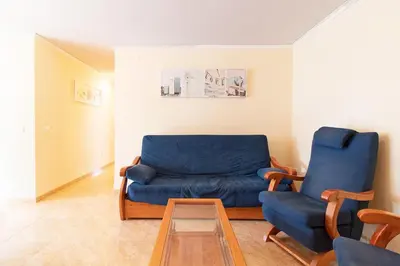 a living room with a blue couch and two chairs at Global Vacacional, Apartamento con piscina y terraza en Canet playa in Canet de Berenguer