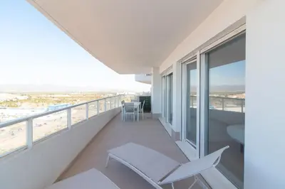 a balcony with a white chair and a view of the beach at Global Vacacional, Moderno apartamento con dos terrazas con vistas al mar y a la montaña in Canet de Berenguer