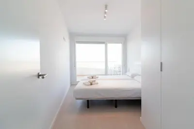 a white bedroom with a bed and a window at Global Vacacional, Moderno apartamento con dos terrazas con vistas al mar y a la montaña in Canet de Berenguer