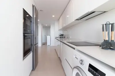 a white kitchen with a sink and a stove at Global Vacacional, Moderno apartamento con dos terrazas con vistas al mar y a la montaña in Canet de Berenguer