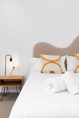 a bed with white sheets and orange pillows at Belmar Apartments in Valencia