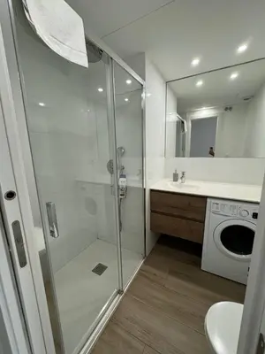 a bathroom with a shower and a washing machine at Escolano Rooms MAS 11 Noches in Valencia