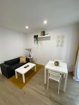 a living room with a black couch and white tables at Escolano Rooms MAS 11 Noches in Valencia