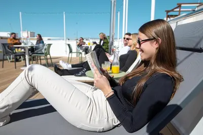 a woman sitting in a chair reading a book at Aila II Hotel Boutique by SingularStays - Digital Access in Burjasot