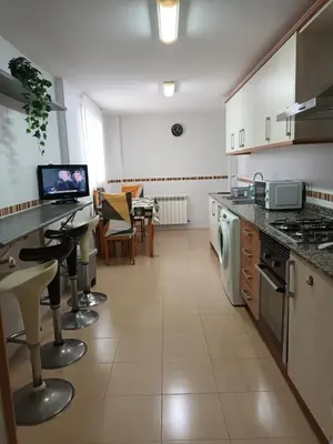 a large kitchen with a counter and chairs in it at Piso amplio de 3 habitaciones, calefacción, ascensor y parking in Burriana