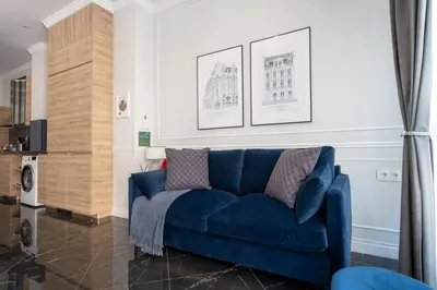 a blue couch in a living room with paintings on the wall at Le Parisien de COUP DE COEUR APPARTEMENTS in Valencia