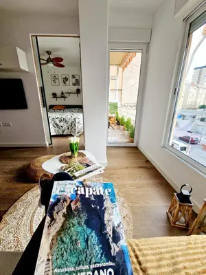 a living room with a large window and a table at Cozy Rustic Home in Playa Pobla de Farnals