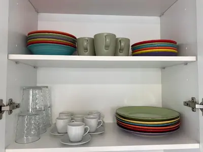a shelf filled with plates and cups and bowls at VerdeMar 5 (Playa Puerto de Sagunto) in Puerto de Sagunto